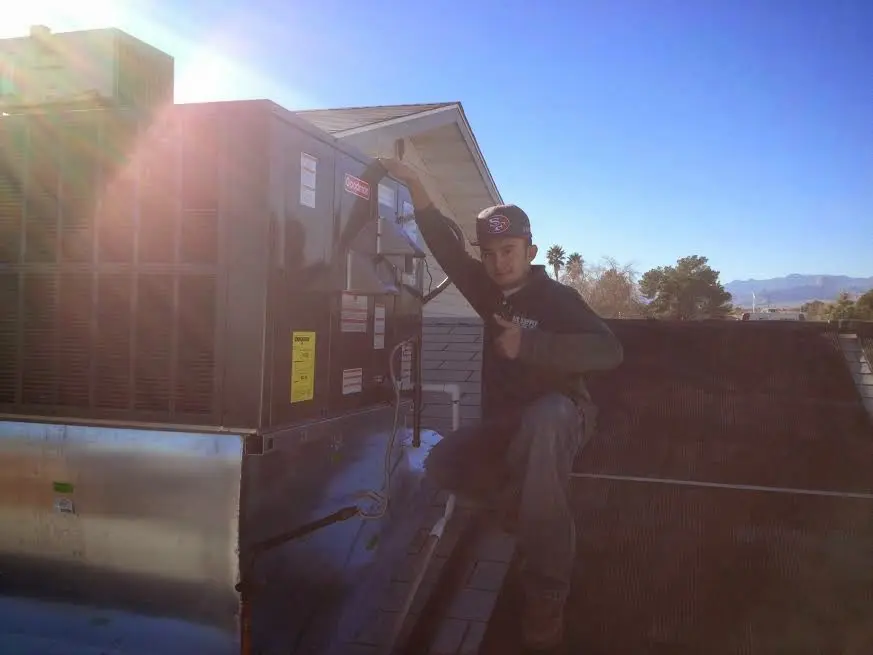 HVAC technician performing AC Tune-Up on a rooftop unit in Prunedale